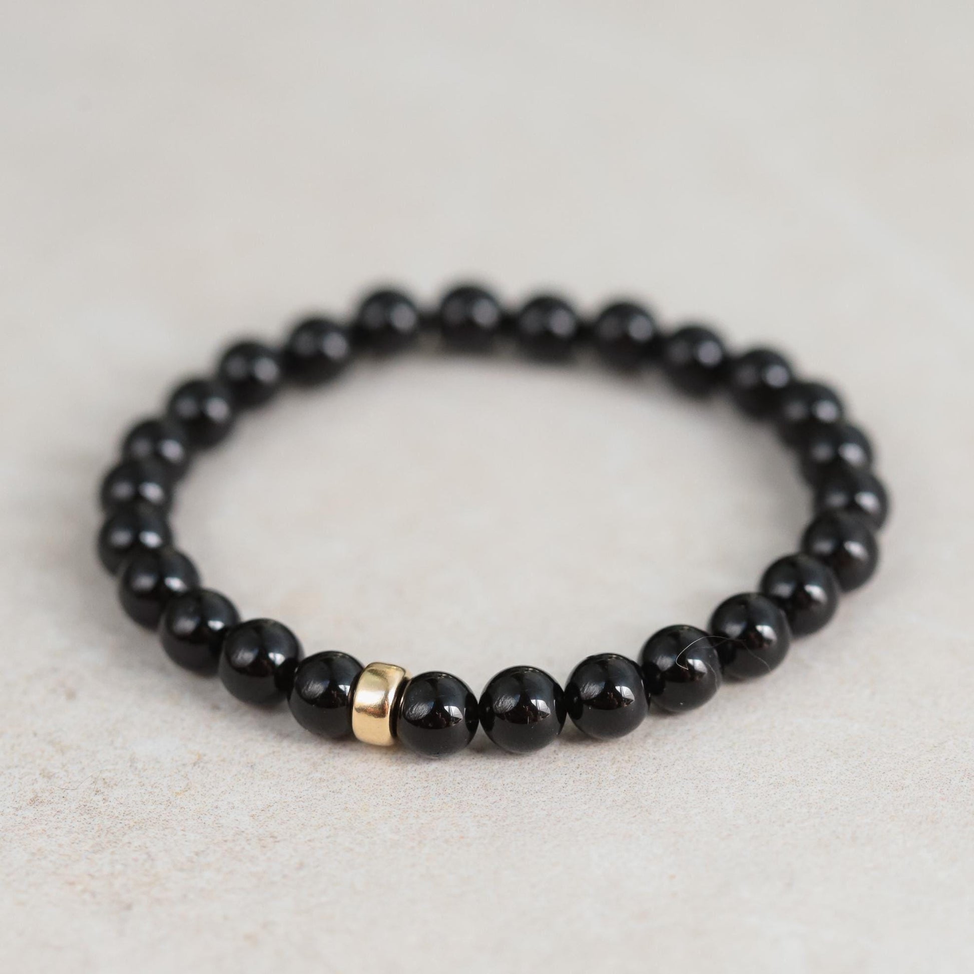 Black tourmaline bracelet by Earthly Abundance Jewelry featuring smooth, protective black stones on a stretch band.