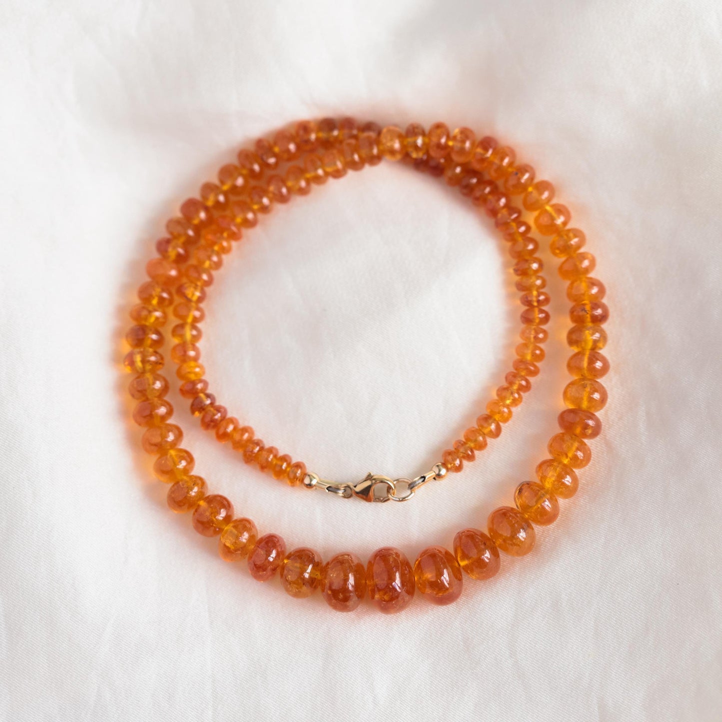 Spessartite Garnet necklace with 14K gold chain from Earthly Abundance, featuring vibrant orange-red gemstones on a delicate chain.