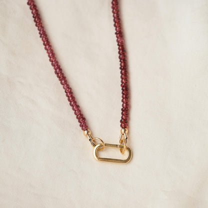 Garnet carabiner necklace with a silver-tone clasp from Earthly Abundance, featuring a polished garnet pendant on a metal chain.