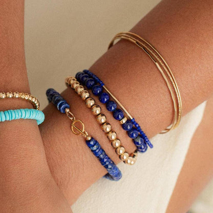 Lapis Lazuli bracelet with polished blue stones from Earthly Abundance Jewelry, showcasing a beaded design on a soft background.