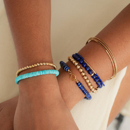 Lapis Lazuli toggle bracelet by Earthly Abundance featuring deep blue stones with gold accents on a white background.