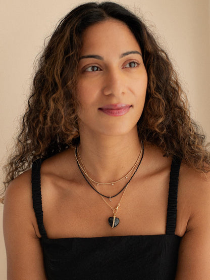 Black spinel moon necklace with 14K gold chain from Earthly Abundance, featuring a polished black spinel moon pendant.