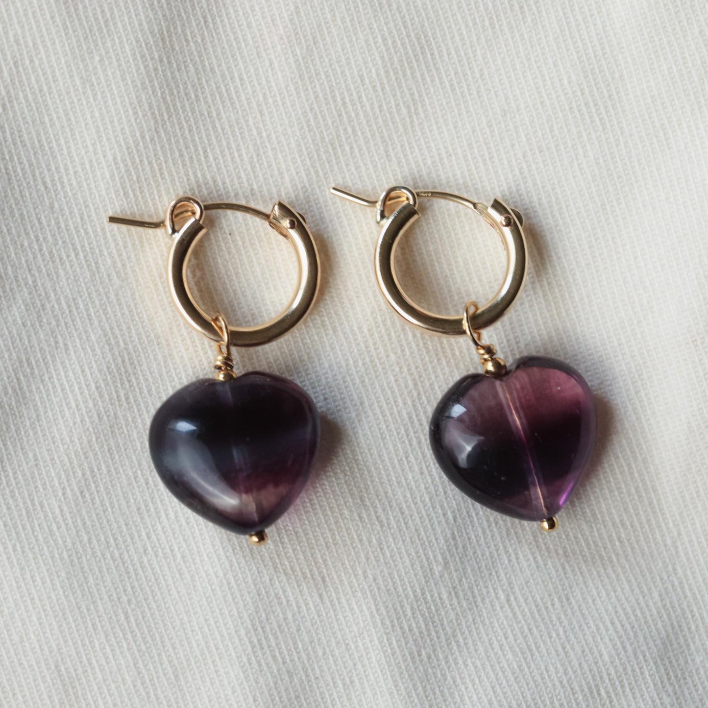 Earthly Abundance fluorite heart hoop earrings featuring vibrant green and purple fluorite stones set in silver hoops.