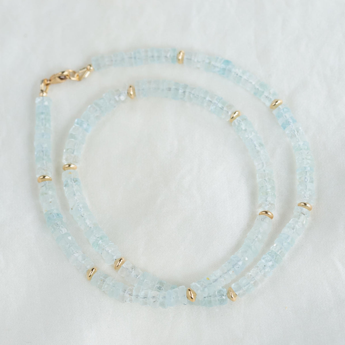 Blue Topaz Heishi necklace featuring small, round blue topaz beads from Earthly Abundance, displayed on a neutral background.