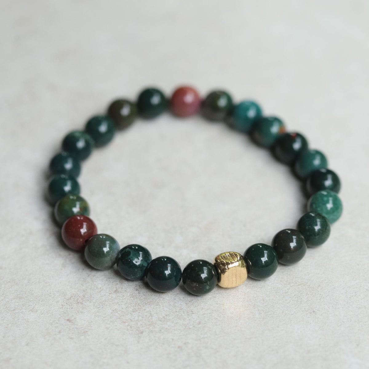 Earth Energy Bloodstone bracelet featuring polished bloodstone beads on a stretch cord, showcased in a close-up shot.