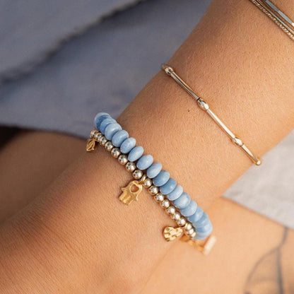 Blue opal bracelet with coastal-inspired heart charm from Earthly Abundance, featuring polished beads on a delicate elastic band.