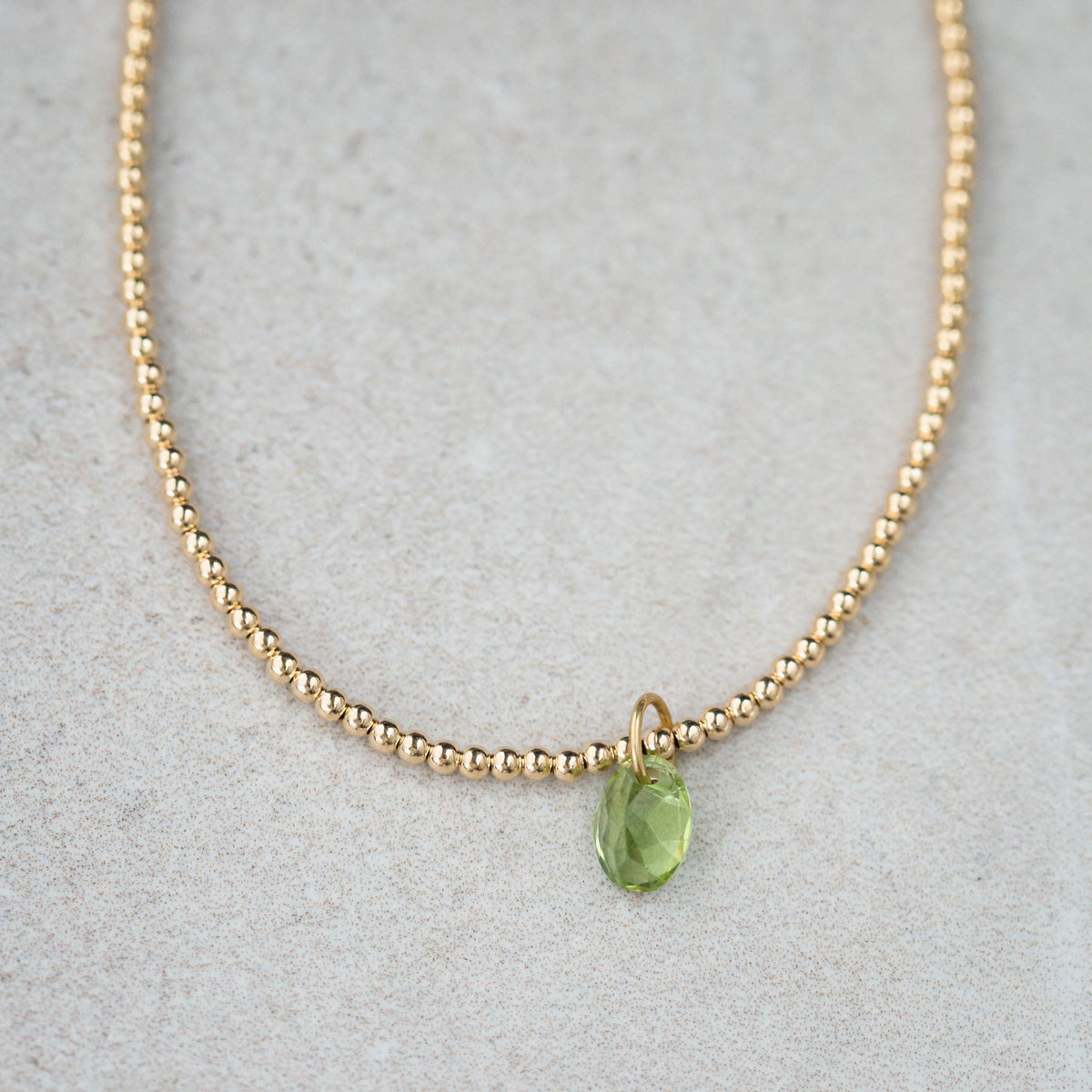 Peridot pendant necklace in 14K gold with a green gemstone, featuring a delicate chain and elegant design.