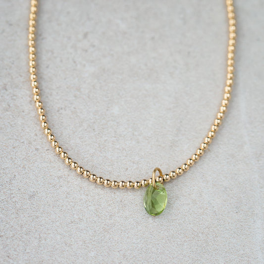 Peridot pendant necklace in 14K gold with a green gemstone, featuring a delicate chain and elegant design.