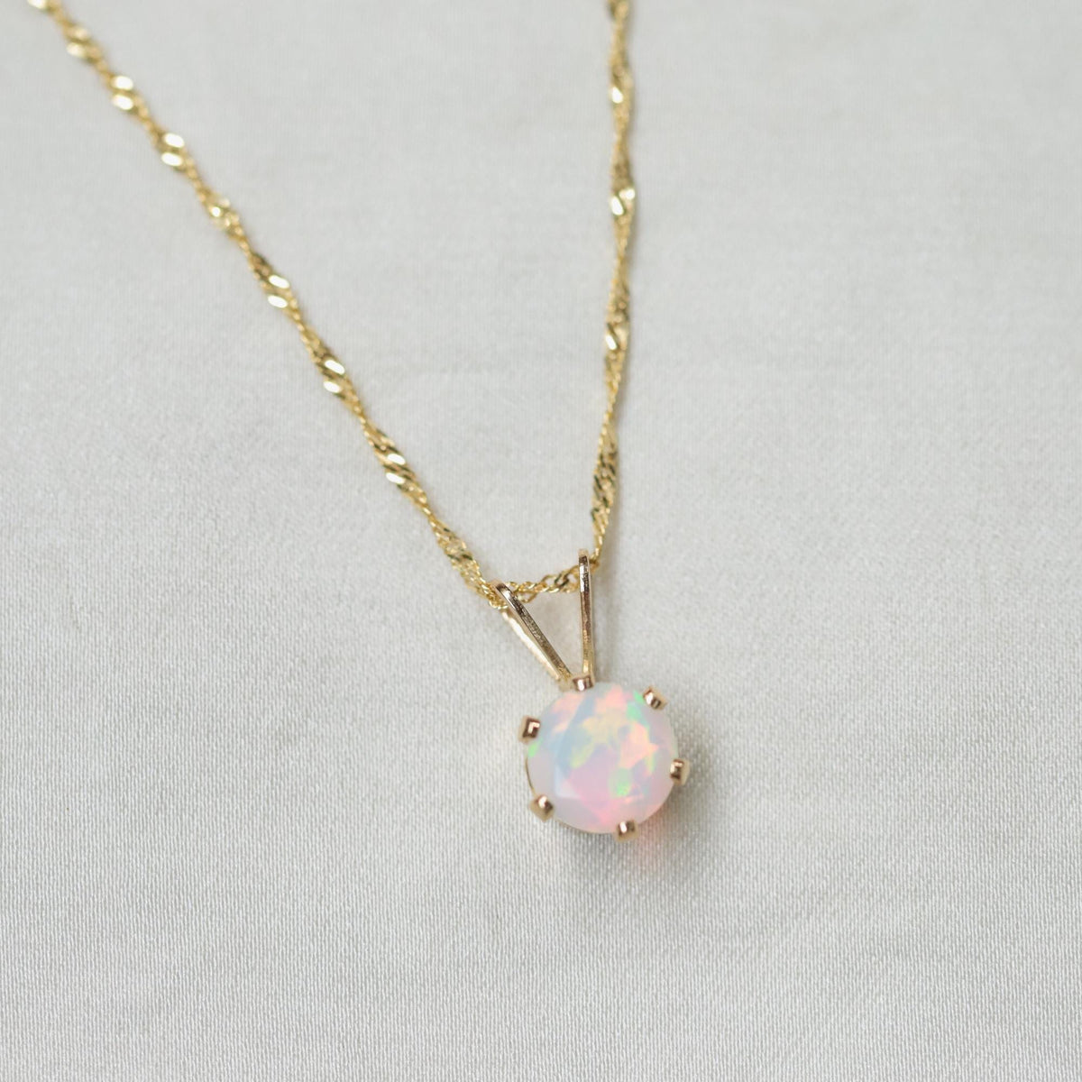 Ethiopian Opal pendant necklace featuring a vibrant, oval-shaped opal set in a 14K gold bezel on a delicate chain.