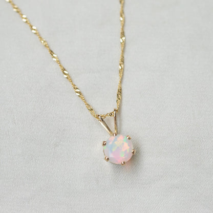 Ethiopian Opal pendant necklace featuring a vibrant, oval-shaped opal set in a 14K gold bezel on a delicate chain.