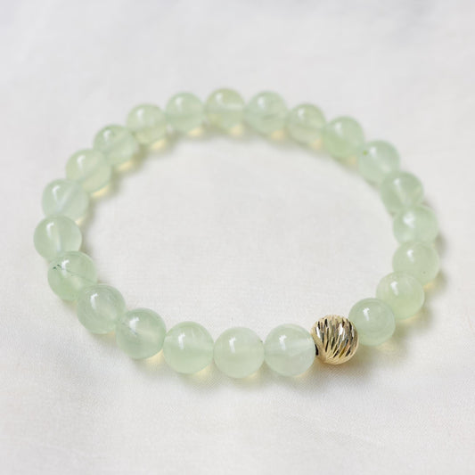 Green glow Prehnite bracelet featuring polished round beads, handcrafted by Earthly Abundance, displayed on a neutral background.