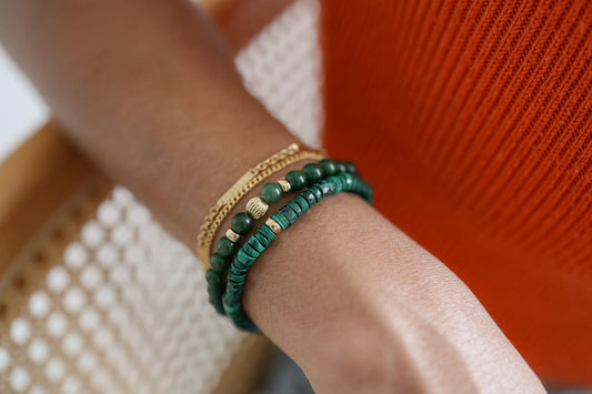 Earthly Abundance Malachite Heishi bracelet with polished green stone beads on an elastic band, close-up view.