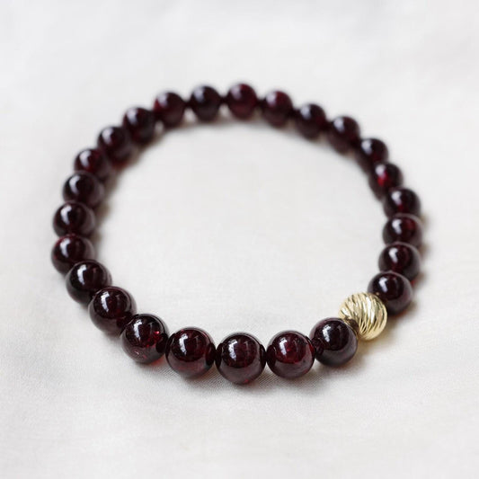 Dark red garnet bracelet with solid 14K gold setting, featuring polished gemstone beads and intricate gold clasp design.