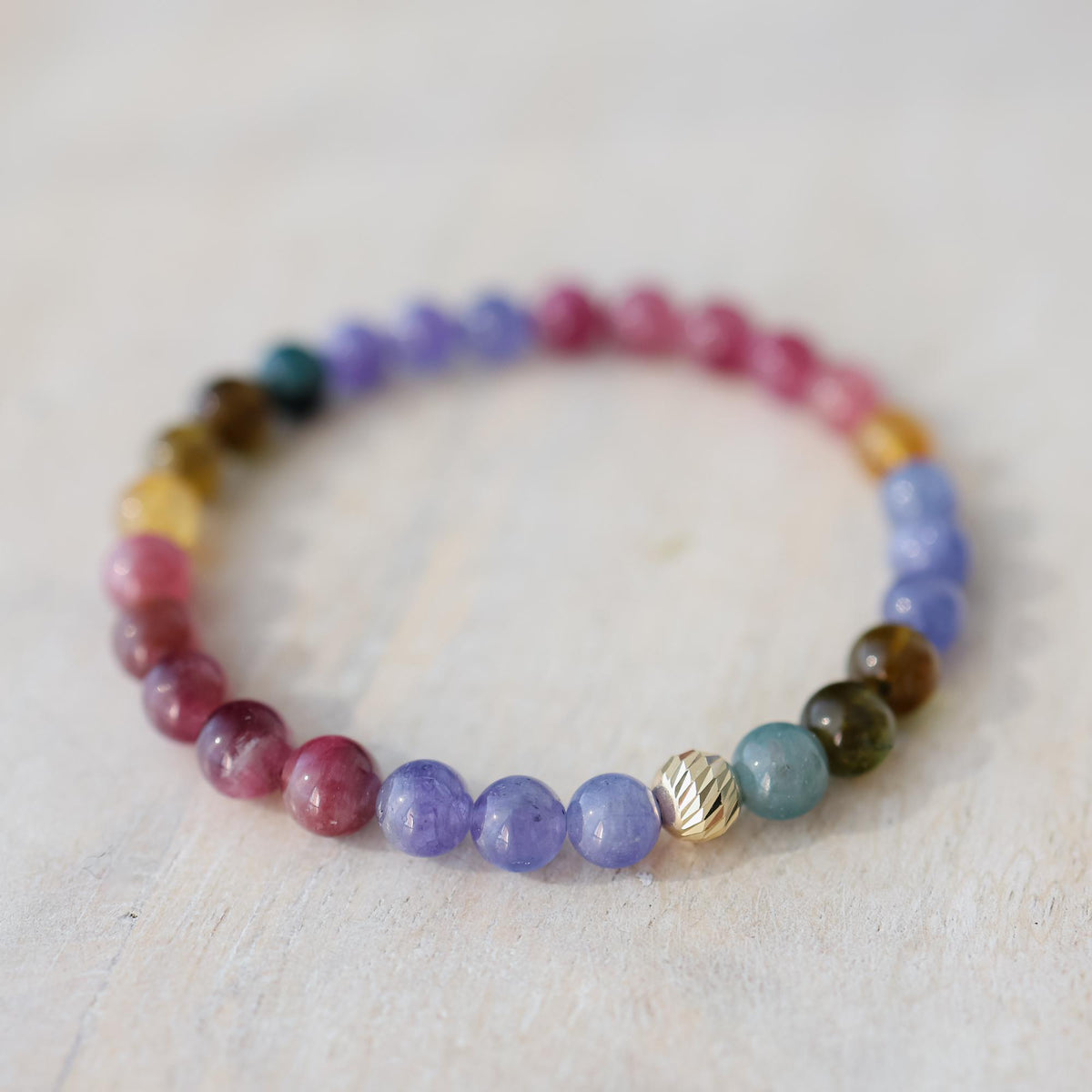 Earthly Abundance Cosmic Candy bracelet featuring vibrant tourmaline and tanzanite gemstones on a delicate silver chain.