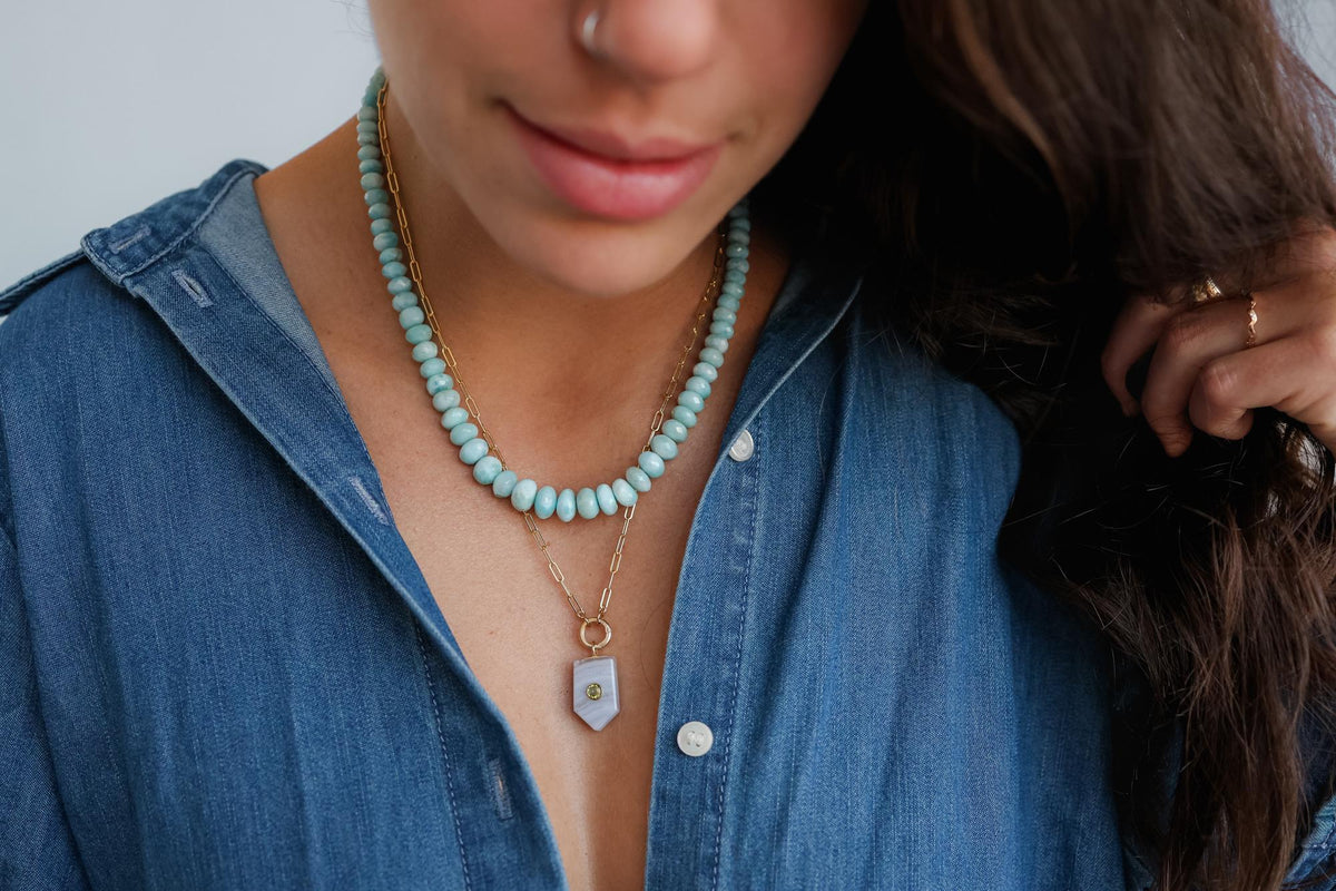 Caribbean Blue Larimar necklace with polished pendant on a silver chain, featuring vibrant blue and white marbled stones.